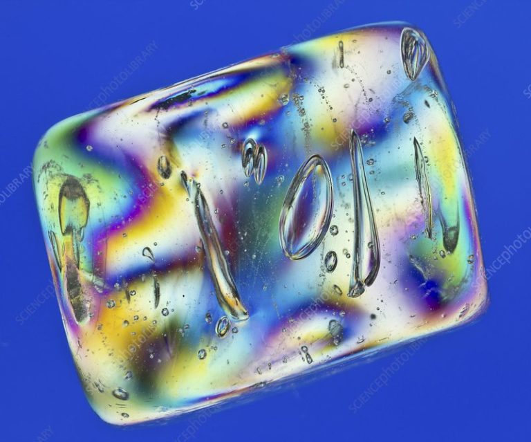 Coloured light interference pattern of a plastic ice cube. When photographed through cross-polarised white light some transparent plastics display coloured interference effects, according to the pattern of residual stress within the plastic (a result of moulding manufacturing). Areas of similar colour represent regions under similar degrees of stress. This phenomenon, known as photoelasticity, is utilised in engineering situations. Plastic models of bridges, gears, axles, etc may be made and subjected to proportional loads in order to predict the stress patterns that might occur in the real objects.